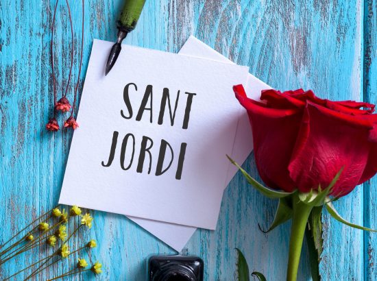 high angle view of a red rose, an ink bottle, a nib pen and the text Sant Jordi, the name of Saint George Day in Catalan, when it is tradition to give red roses and books in Catalonia, Spain